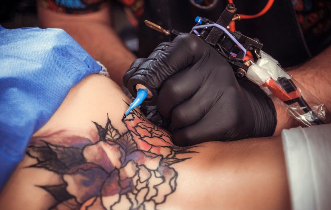 Donde desechar agujas de tatuaje. Aparece una persona realizando un tatuaje.